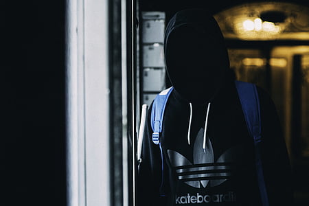 person wearing black and gray adidas pullover hoodie and blue backpack standing beside clear glass panel during daytime thumbnail