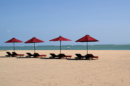 four red patio umbrellas in front of beach thumbnail