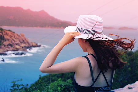 woman wearing white sunhat on mountain cliff over-viewing sea thumbnail