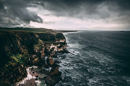 rocky cliff beside body of water thumbnail