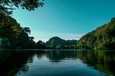 body of water between green leafed trees during daytime thumbnail