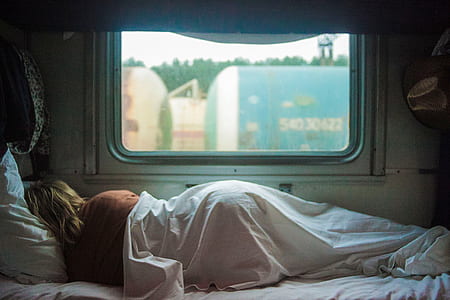 person lying on bed near window thumbnail