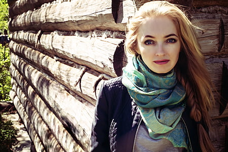 woman wearing black jacket and green scarf standing behind wood fence thumbnail