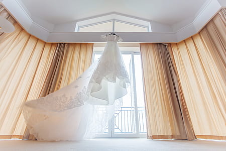 white wedding gown near window curtain thumbnail
