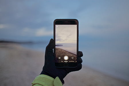 person taking photo of seashore thumbnail
