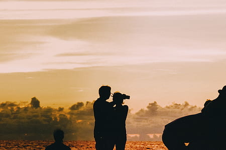 silhouette of couple standing under orange sky thumbnail