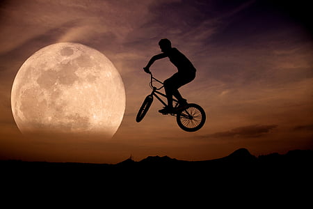 silhouette of man riding bicycle on mid air during sunset thumbnail