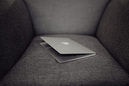 Close up view of closed laptop lying on grey armchair thumbnail