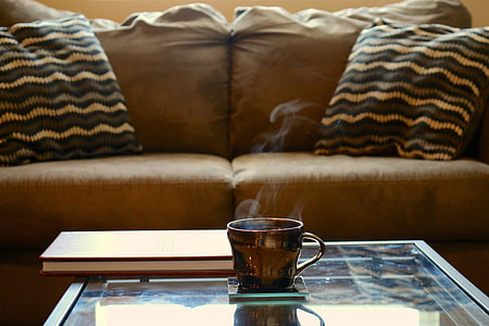 brown ceramic teacup on glass-top coffee table beside brown sofa thumbnail