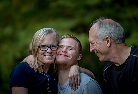 woman holding boy beside man near green leaf tree thumbnail