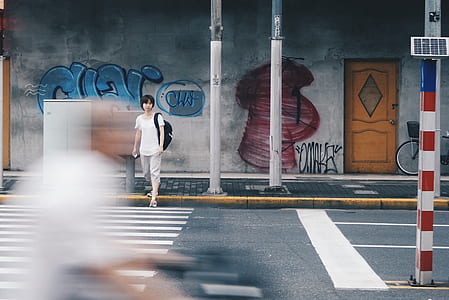woman crossing pedestrian lane while carrying black backpack during daytime thumbnail