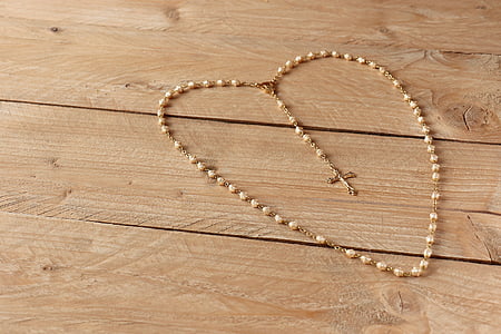 beige rosary on beige wooden frame thumbnail