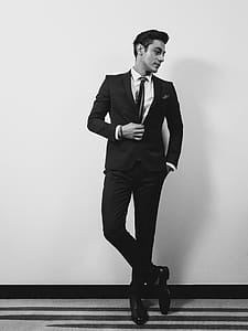 Man Wearing Suit Jacket, Dress Shirt, and Dress Pants Standing Near Wall thumbnail