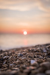 selective focus photography of pile of stone near seashore during sunset thumbnail