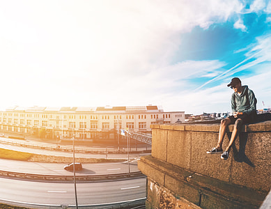 man wearing gray hooding sitting on edge of building thumbnail
