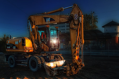 yellow Caterpillar excavator near concrete buildings thumbnail