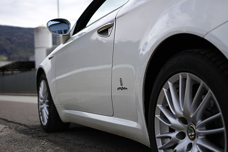white Alfa Romeo car parked on road thumbnail