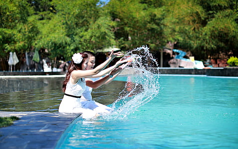 two girls playing in swimming pool during daytime thumbnail