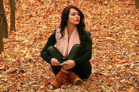 woman wearing long sleeve shirt and pants sitting on dry leaves during daytime thumbnail