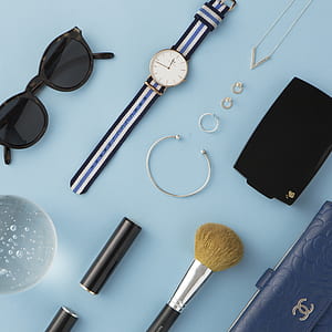 round gold-colored watch near sunglasses and makeup brush thumbnail
