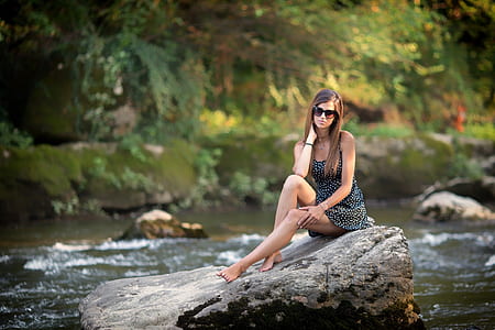 woman in black sleeveless dress on rack near lake thumbnail
