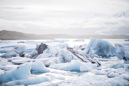 snow bergs near green land under white clouds during daytime thumbnail