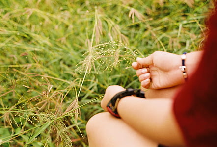 woman holding grass while sitting on grass thumbnail