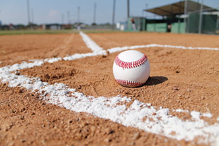 white and red baseball on brown sand thumbnail