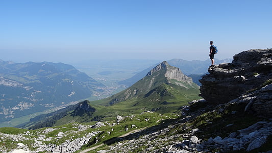 man standing on rock overlooking mountain at daytime thumbnail