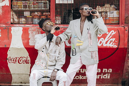 Two Person Drinking Coca-cola Next to a Kiosk thumbnail