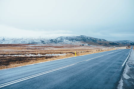 mountains near concrete road under cloudy sky thumbnail