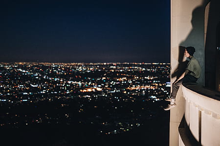 man sits on building with near cities during nighttime thumbnail