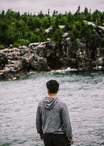 man standing in front of body of water during daytime thumbnail