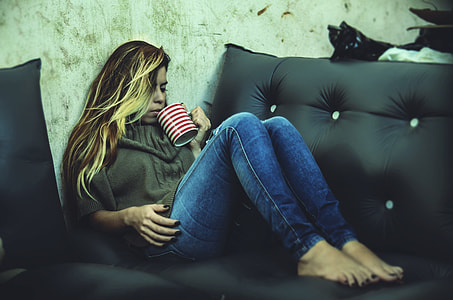 woman holding mug while sitting on sofa \ thumbnail