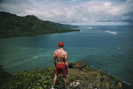 man standing on cliff surrounded by water during daytime thumbnail