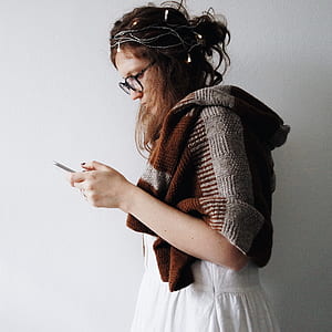 woman in white dress standing holding Android smartphone thumbnail