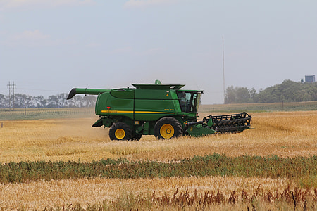 green combine harvester in the middle of field taken at daytime thumbnail