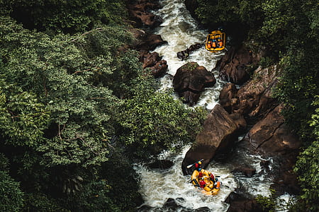 group of people on yellow inflatable boats rowing between rock formation thumbnail