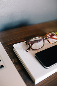 brown framed eyeglasses beside smartphone on table thumbnail
