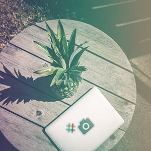 Pineapple Fruit Near White Laptop Computer on Brown Wooden Table thumbnail
