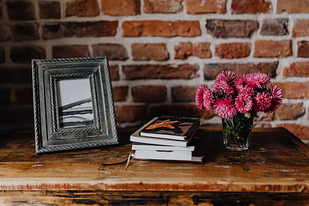 Photo frame, books and pink flowers in a vase on a wooden commode thumbnail