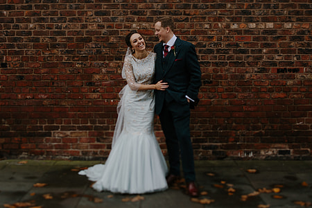 man and woman standing beside red brick wall thumbnail
