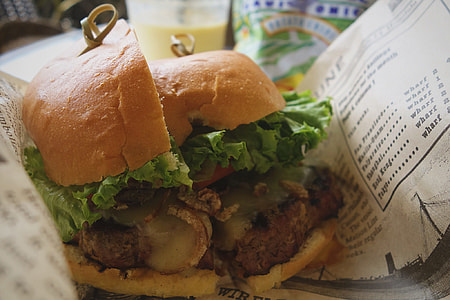 hamburger with lettuce sliced in half in on white paper thumbnail