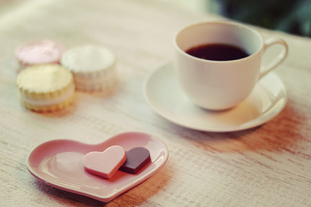 white ceramic teacup with plate on table with macaroons and heart-shaped plate thumbnail