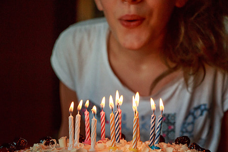 woman wearin ggray printed shirt blowing candle in cake thumbnail