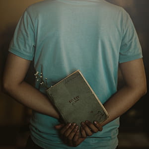 Man Wearing T-shirt Holding Book thumbnail