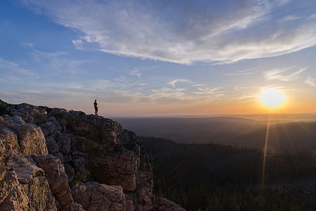 person standing on brown mountain during sunset thumbnail