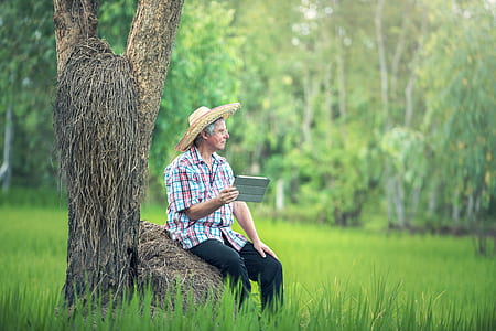 man sitting on brown rock during daytime while holding and gray tablet computer smart case thumbnail