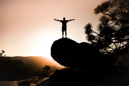 man standing on rock during sunset thumbnail