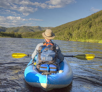 man riding on blue inflatable raft holding oar thumbnail